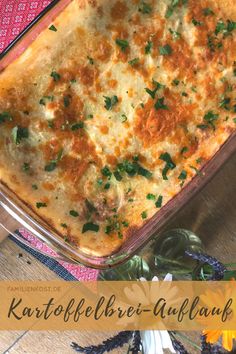 a casserole dish with cheese and parsley in it on a wooden table