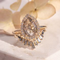 a close up of a diamond ring with flowers in the background