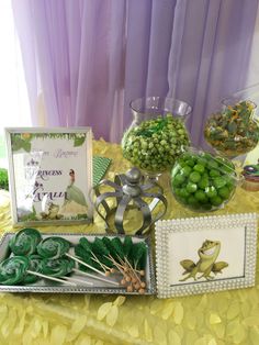 a table topped with lots of green candies next to framed pictures and other items