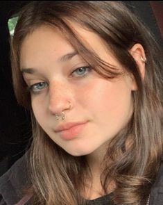 a young woman with piercings on her nose sitting in the back seat of a car