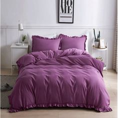 a bed with purple sheets and pillows in a room