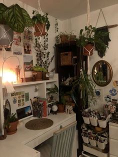 a room filled with lots of potted plants next to a white desk and chair