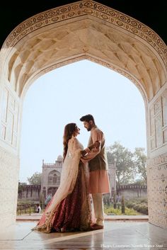 a man and woman standing in front of an archway