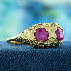 Adorn your fingers with this exquisite Natural Double Ruby Edwardian Style Filigree Solid Gold Ring. Crafted from solid yellow gold, this stunning piece showcases two vibrant natural rubies, set against a beautifully intricate filigree design that echoes the sophistication of the Edwardian era. With a carefully balanced size that fits comfortably on the hand, this ring makes a striking statement while still being versatile enough for everyday wear. CHARACTERISTICS Status: Made to order Origin: Thailand Metal: Solid 9K Yellow Gold Ring Size: US 3-8 Total Gemstones Weight: 1.00 carat. (approx.) Total Gram Weight: 2.90 g. (approx.) *Pictures have been enlarged to show details* PRIMARY STONE(S) Stone: Natural Ruby Color: Red Shape: Round Size: 5 mm. Number: 2 Weight: 1.00 Carat (approx.) An at Edwardian Style, Solid Gold Ring, Filigree Design, Edwardian Era, Edwardian Fashion, Solid Gold Rings, Multi Stone Ring, Natural Ruby, Gold Design