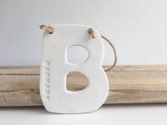 a white wooden letter sitting on top of a piece of wood next to a rope