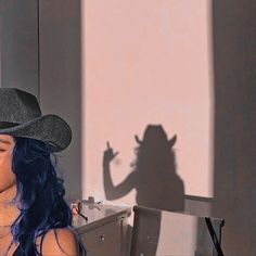 a woman with blue hair wearing a black cowboy hat and holding a microphone in her hand