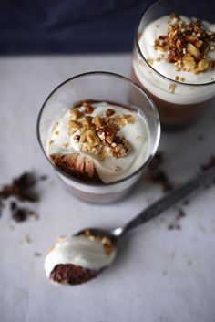 two glasses filled with dessert sitting on top of a table