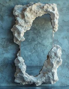 a mirror that is on the wall in front of a blue stone background with water below it