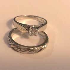 two wedding rings sitting side by side on top of each other with a diamond in the middle