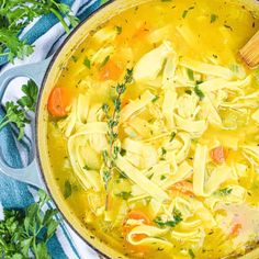 a bowl of chicken noodle soup on a blue and white towel with parsley