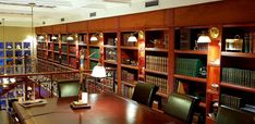 an empty library with many bookshelves and lamps on the tables in front of them