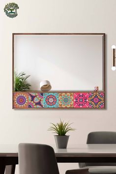 a mirror hanging on the wall above a table with chairs and a potted plant