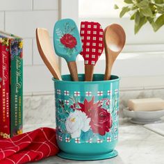 four wooden spoons are in a blue cup with flowers and leaves on the handle