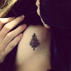 a woman's arm with a small tree tattoo on the left side of her body