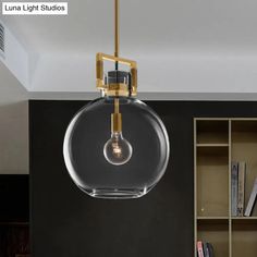 a clear glass pendant light hanging from a ceiling in a room with bookshelves