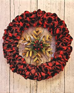 a red and black christmas wreath hanging on a wooden wall