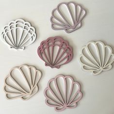 four seashell cookie cutters are shown on a white surface with pink trimming