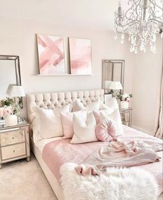 a bedroom with pink and white decor, chandelier, pillows and blankets on the bed