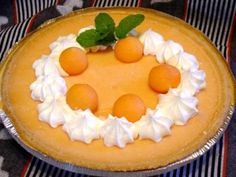 a pie with whipped cream and oranges on top is sitting on a tablecloth