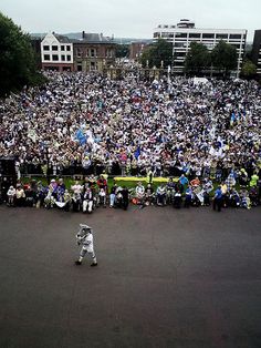 a large group of people sitting in the middle of a street watching a man on a skateboard