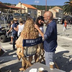 a man and woman hug each other in front of an outdoor cafe on the beach