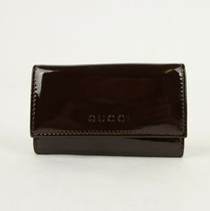 a brown leather business card case on a white surface with the word gucci written in cursive writing