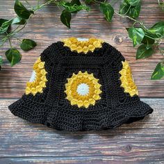 a crocheted black and yellow hat sitting on top of a wooden table