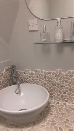 a white sink sitting on top of a counter next to a wall mounted faucet