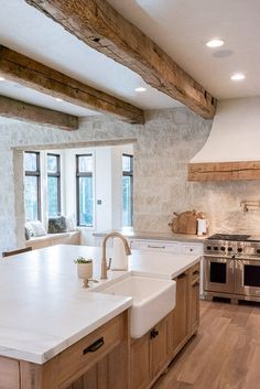 a large kitchen with an island in the middle and wood beams on the ceiling above it