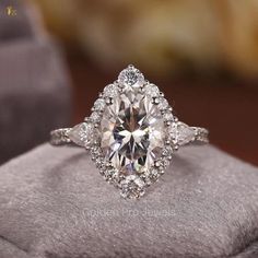 an oval cut diamond ring on top of a cushion