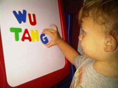 a young boy writing on a white board with colorful letters in the shape of words