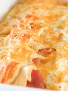 a casserole dish with ham, cheese and potatoes in a white baking dish