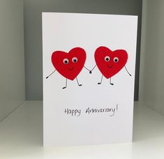 two hearts holding hands with the words happy anniversary written on them, in front of a white background