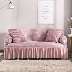 a living room with a pink couch and white rug