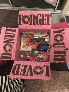 a pink box filled with donuts and other items sitting on top of a table