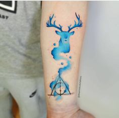 a blue ink tattoo on the arm of a person with a triangle and deer head