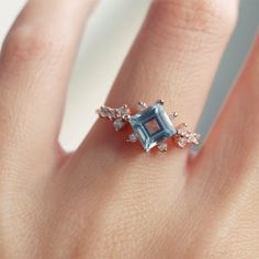 a woman's hand with a ring that has an aqua blue and white diamond on it