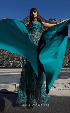 a woman in a long green dress is holding her shawl over her shoulder and posing for the camera