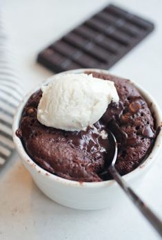 a bowl filled with chocolate pudding and ice cream on top of a table next to a spoon