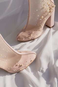 a pair of pink high heeled shoes with pearls on them