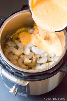 someone is pouring sauce into an instant pot filled with shrimp and other ingredients to make a meal