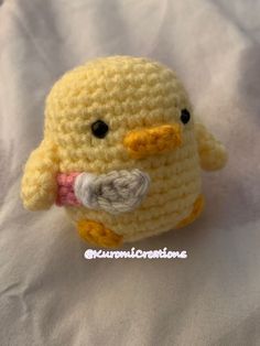 a small crocheted yellow bird sitting on top of a white sheet