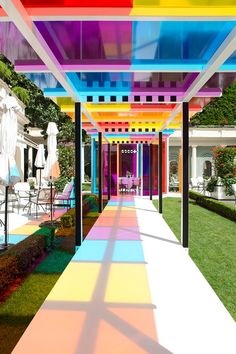 an outdoor area with tables, chairs and umbrellas covered in multicolored paint