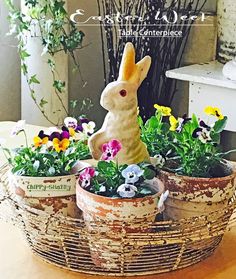 a basket filled with flowers and a statue of a rabbit sitting in it's center