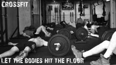 some people laying on the ground with dumbs in front of them and one person holding a barbell