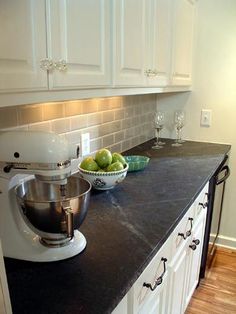 a kitchen counter with a bowl of fruit on top of it and a mixer in the middle