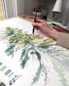 a person is painting on an easel with paintbrushes and watercolors