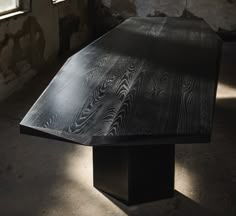 a wooden table sitting in an old room with sunlight coming through the window and casting shadows on the floor