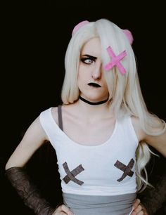 a woman with white hair and black makeup wearing a cross t - shirt while standing in front of a black background