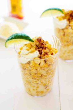 two glasses filled with food sitting on top of a white table next to each other